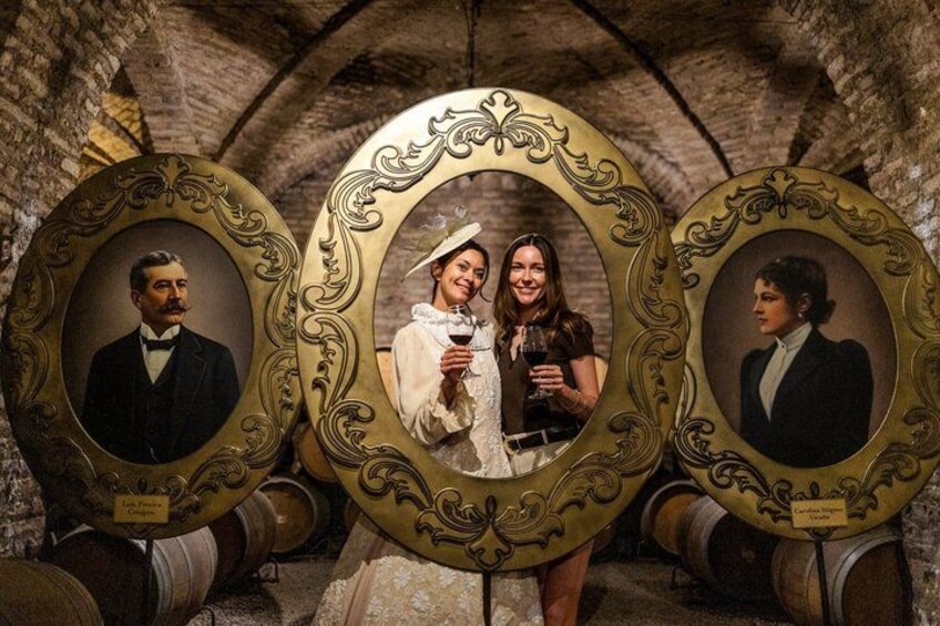 A vintage photo frame with portraits, set against a stone wall with barrels. 2