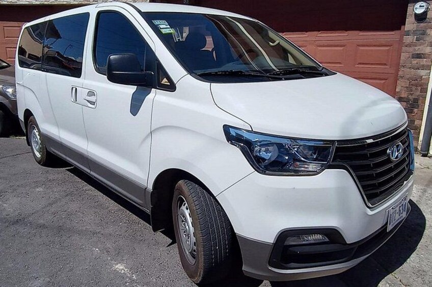 A white minivan parked in front of a garage. 1