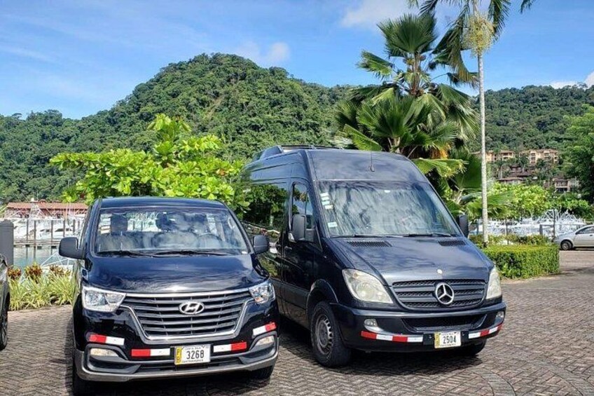 Two vehicles parked on a paved surface with a mountainous landscape in the background. 3