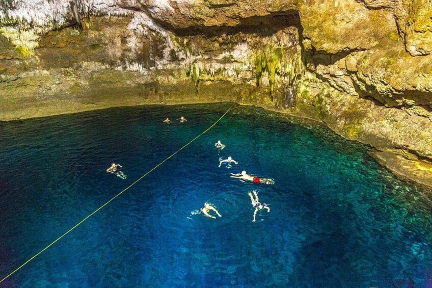 A group of people swimming in a clear blue pool surrounded by rocky cliffs. 4