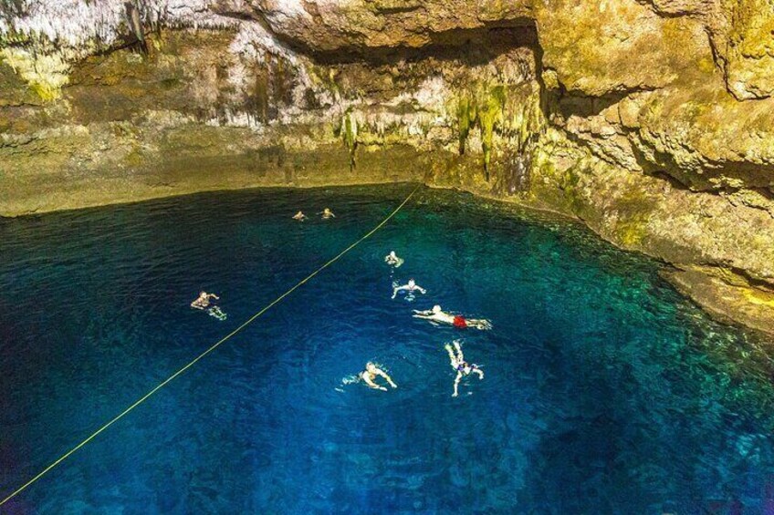A group of people swimming in a clear blue pool surrounded by rocky cliffs. 4