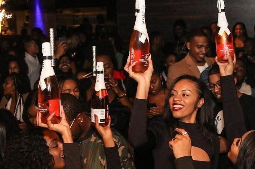 A crowd holding up bottles of a beverage. 4