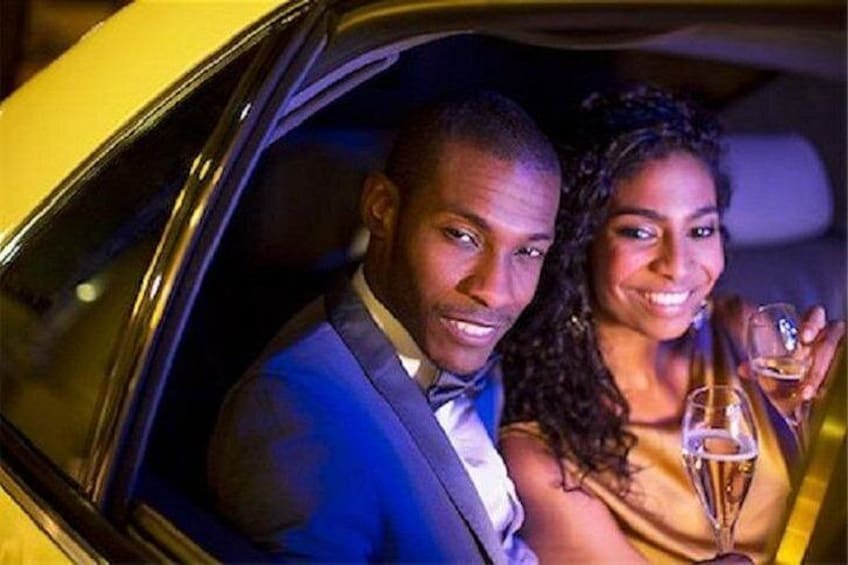 A car interior with a man and a woman holding champagne glasses. 2