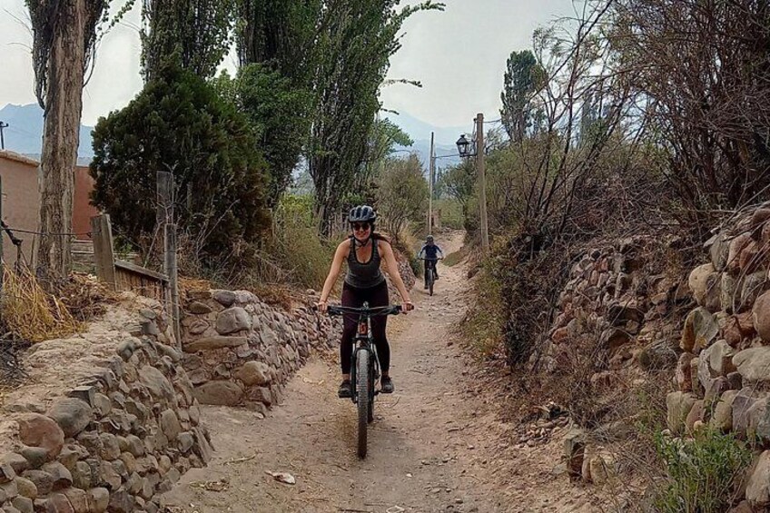 Un chemin de terre bordé de murs de pierre de chaque côté, un cycliste au premier plan et un autre au loin. 5