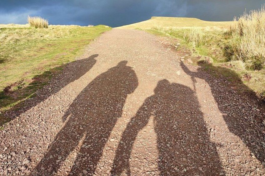 A gravel road with shadows of people on it. 3