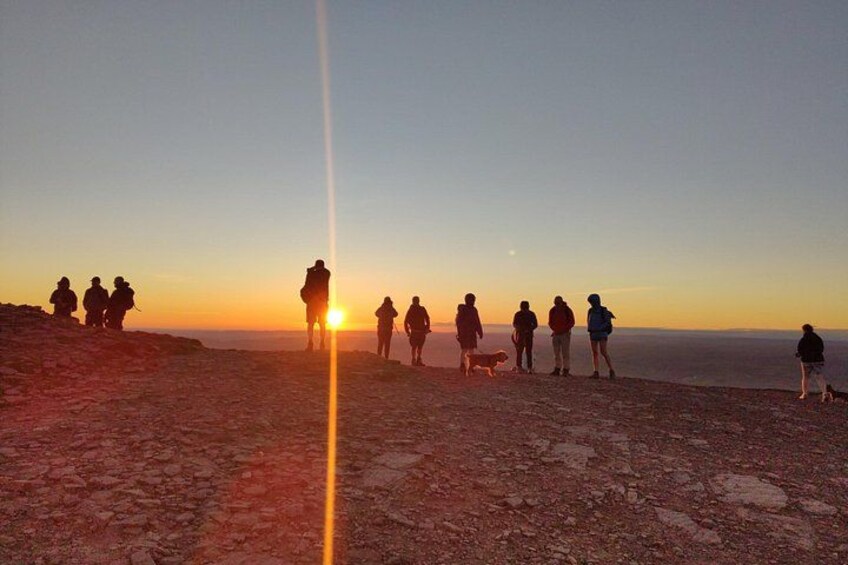 A group of people standing on a rocky beach at sunset. 2