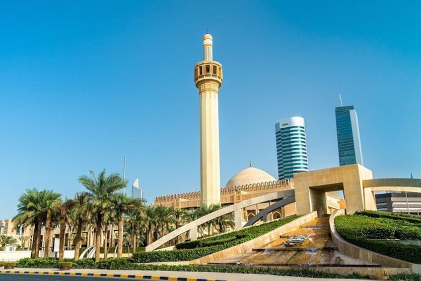 A mosque with a tall minaret, palm trees, and modern buildings in the background. 1