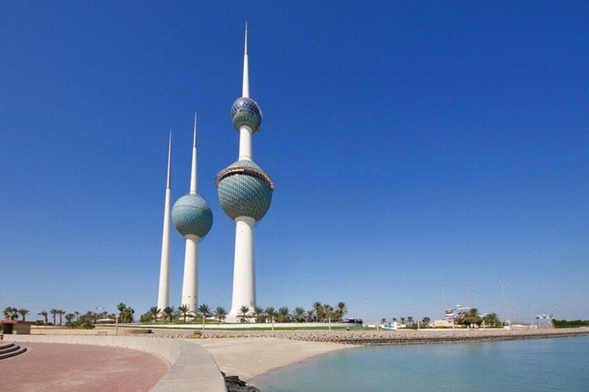 Three tall towers with spherical tops, a clear blue sky, and a calm body of water. 3