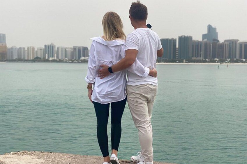 A couple standing by a waterfront with a city skyline in the background. 5