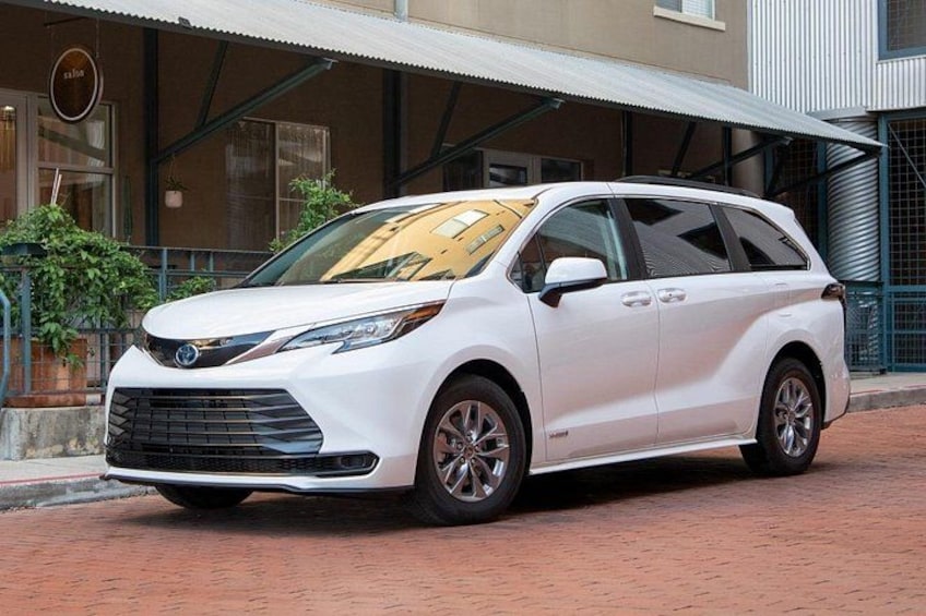 A white minivan parked in front of a building with a metal awning. 2