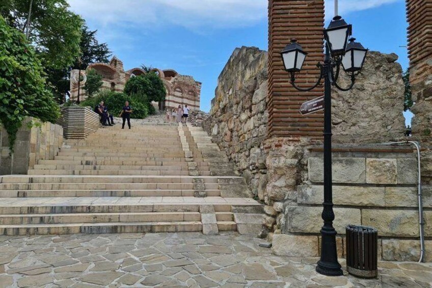 Un escalier en pierre menant à une structure ancienne, avec un lampadaire et une poubelle. 2