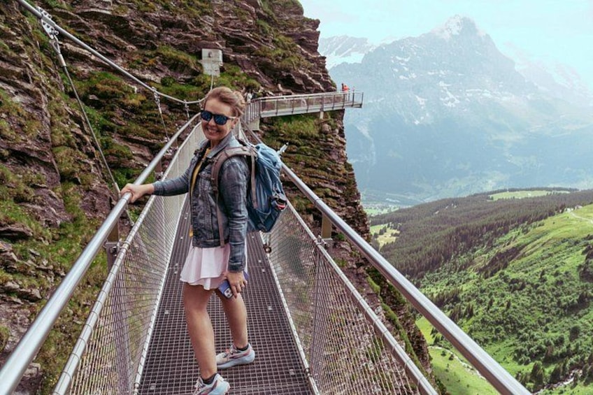A person standing on a metal bridge with a mountainous landscape in the background. 4