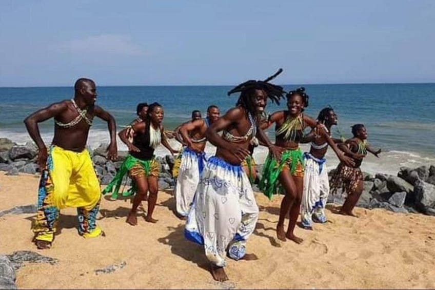 Un gruppo di persone che ballano su una spiaggia sabbiosa, con l'oceano sullo sfondo. 3