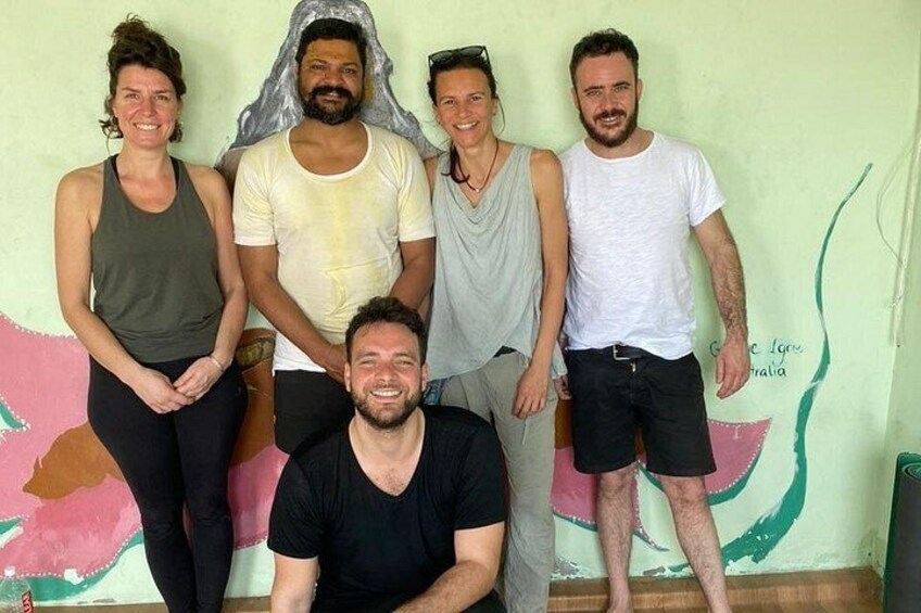 A group of people standing in front of a wall with a painting. 2