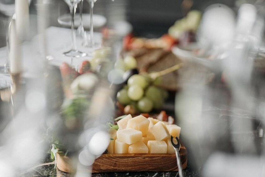 A cheese board with various cheeses and grapes on a wooden board. 3