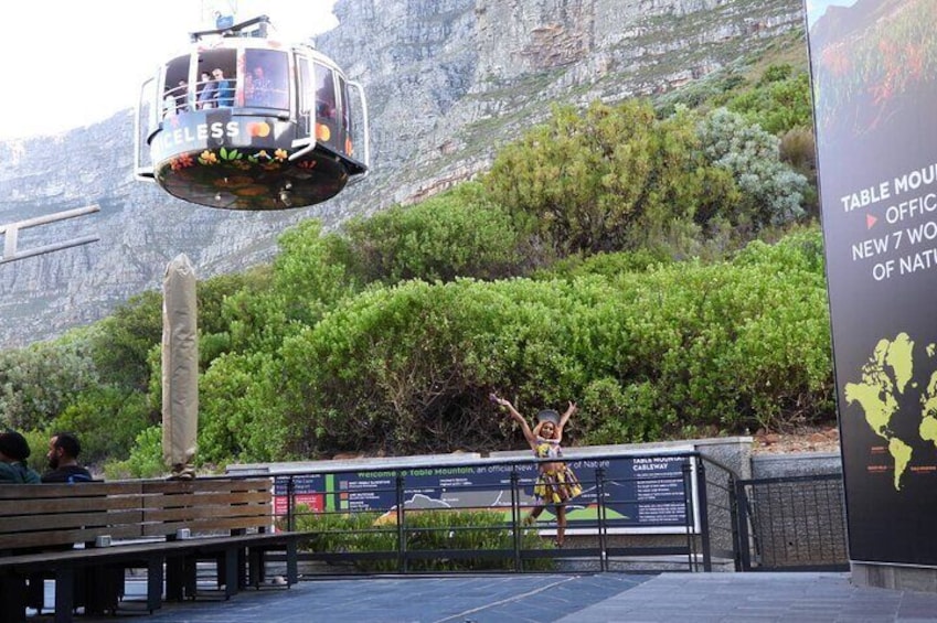 Eine Seilbahn, eine Person mit erhobenen Armen und ein Schild mit Text. 3