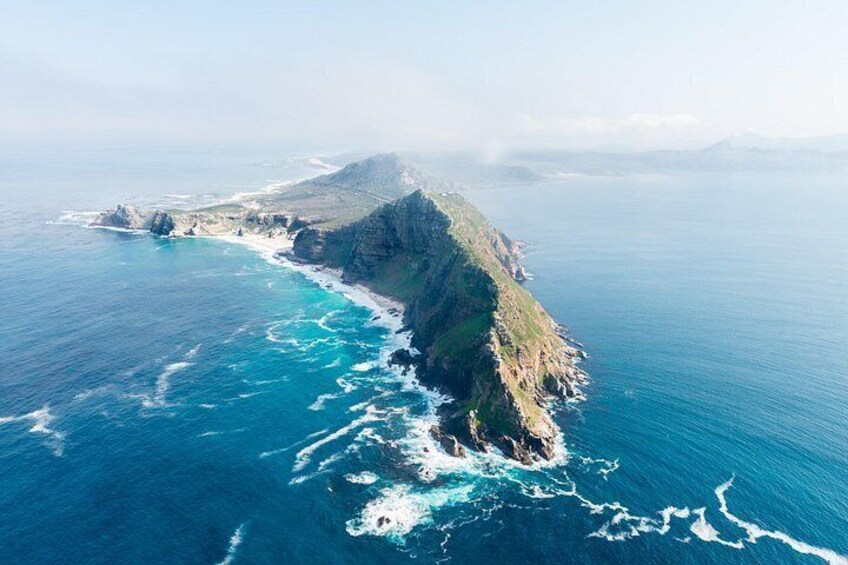 Un paisaje costero con un acantilado imponente, una pequeña isla y un mar azul cristalino. 2