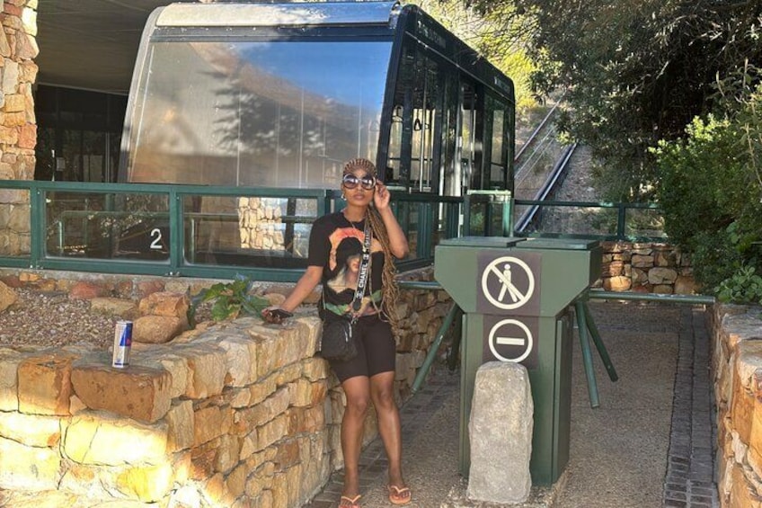 A person standing next to a glass bus shelter with a no-entry sign, a stone wall, and a can on the ground. 4