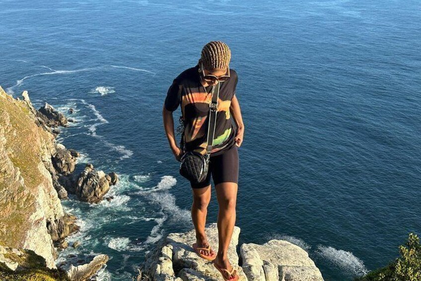 Une personne se tient debout sur une falaise rocheuse, surplombant l’océan. 4