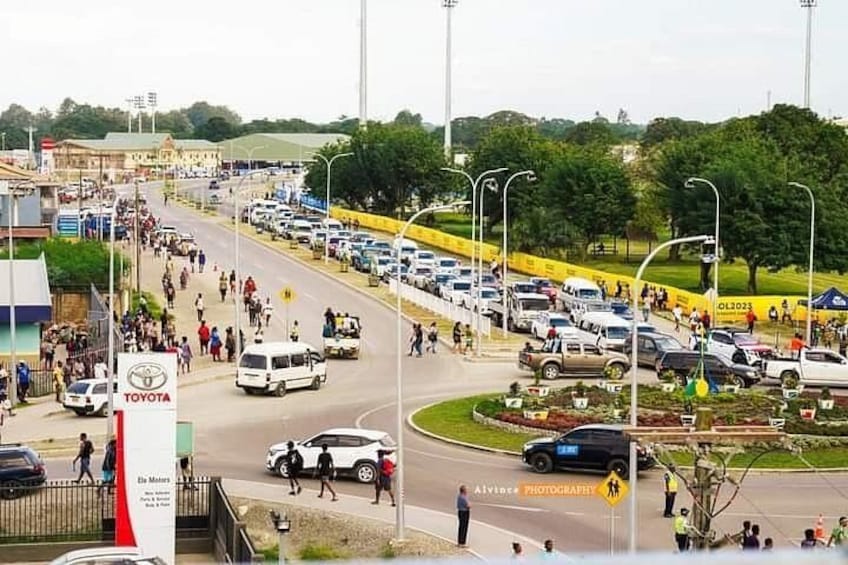 A busy intersection with multiple lanes of traffic, a Toyota dealership sign, and a crowd of people. 1