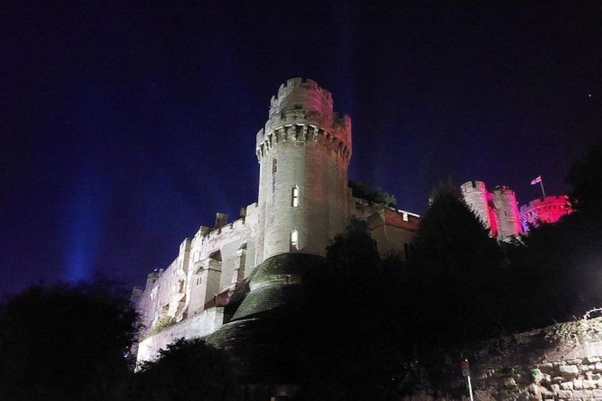 Un castillo iluminado de noche con torres brillantes y una bandera. 2