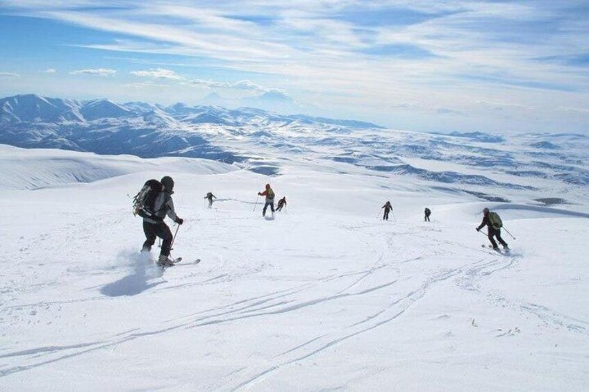A group of skiers on a snowy mountain with clear skies. 2