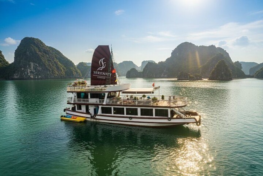 A boat with a red sail on a calm body of water surrounded by rocky islands. 1