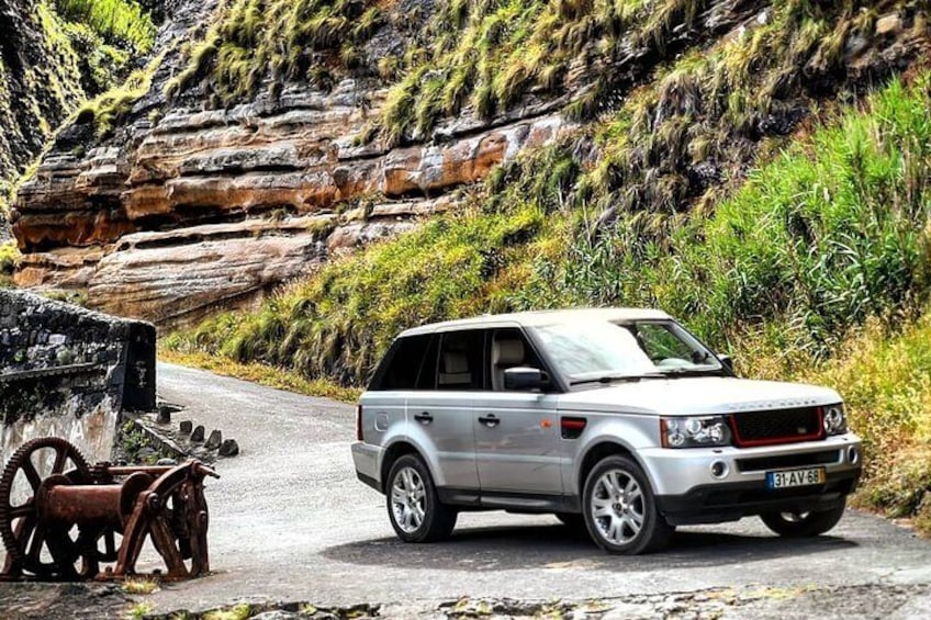 Un SUV argento parcheggiato su una strada, con una collina rocciosa sullo sfondo. 3