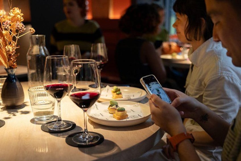 A dining table with wine glasses, a vase with dried flowers, and a person using a smartphone. 5