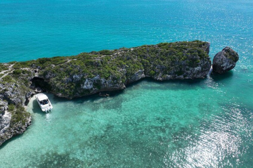 A boat near a rocky coastline with clear turquoise water. 2