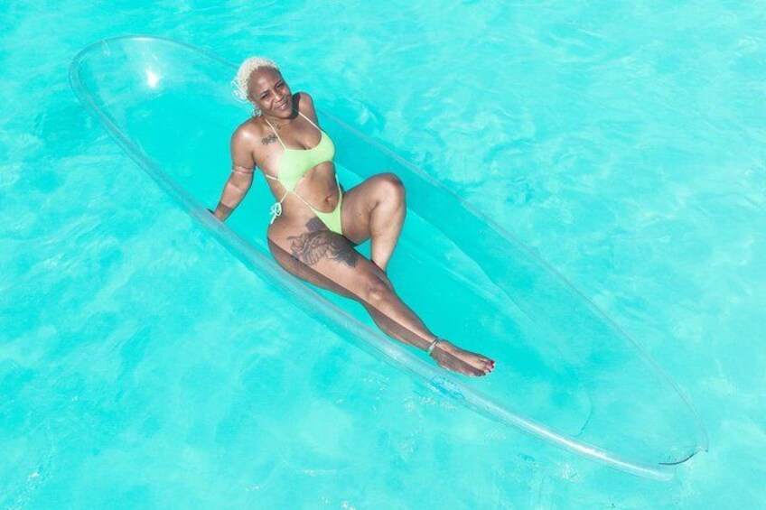 A person lying on a transparent inflatable raft in a clear blue pool. 4