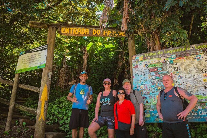 A group of people standing in front of a sign that reads 'ENTRADA DO PARQUE' and another sign with a map. 5