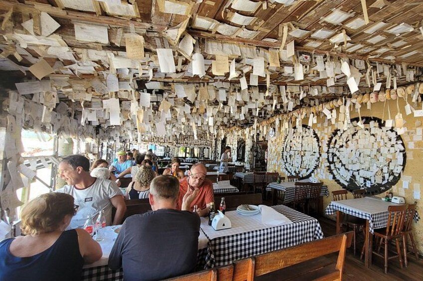 A restaurant with checkered tablecloths and patrons seated at tables. 3