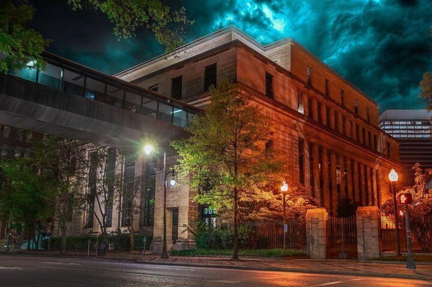 A historic building with a bridge, trees, and street lamps. 5