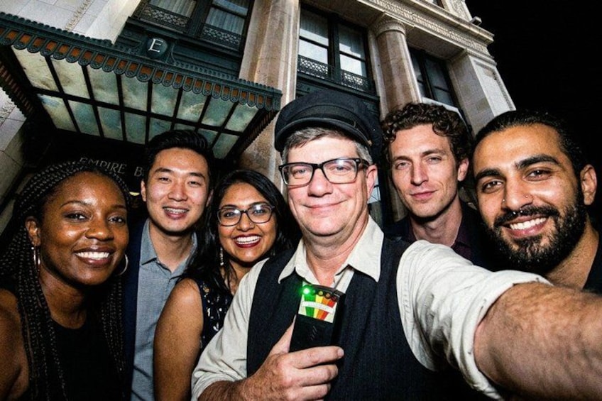 A group of people taking a selfie in front of a building with columns and a balcony. 4
