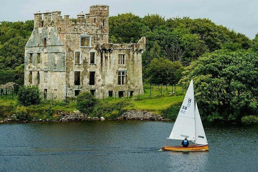 A sailboat on a lake with a historic building in the background. 2