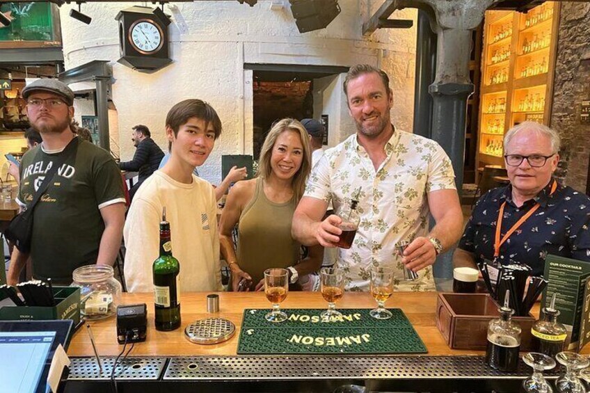 A bar with a green mat, bottles, glasses, and a clock on the wall. 3