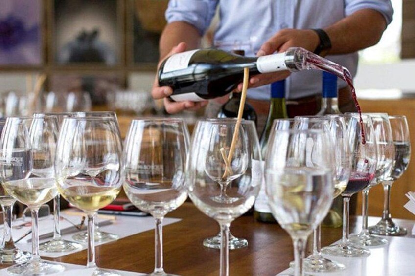 Eine Person gießt Wein in mehrere Gläser auf einem Tisch ein. 2