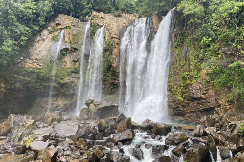 A multi-tiered waterfall surrounded by rocky terrain and lush greenery. 1