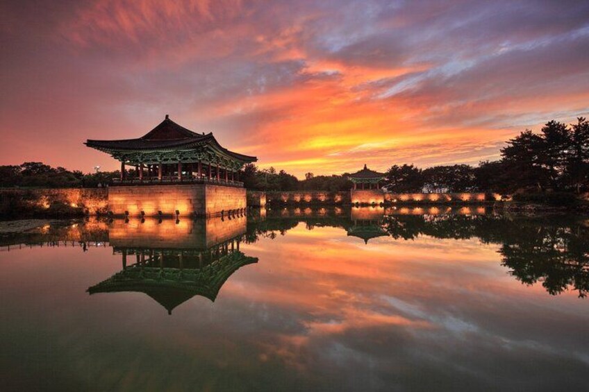 A traditional pavilion reflecting on a calm lake at sunset. 2