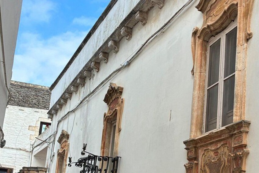 A building with ornate window frames and a balcony with a wrought iron railing. 5
