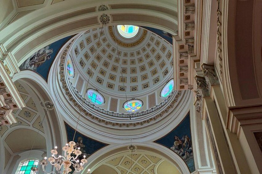 A grand architectural interior with a domed ceiling, ornate moldings, and stained glass windows. 3
