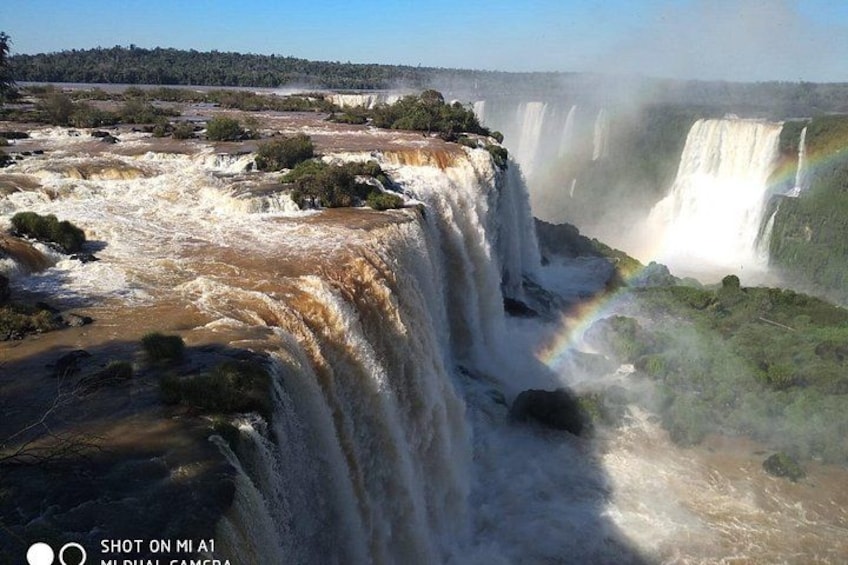 Una cascata con un arcobaleno, immersa nel verde. 1