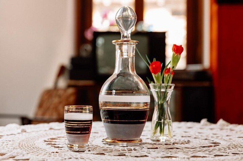 A glass decanter, a glass with a striped pattern, and a vase with red flowers on a lace tablecloth. 3
