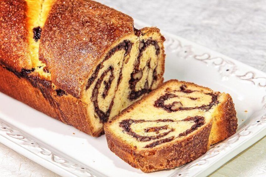 A loaf of bread with a swirl pattern, sliced and placed on a white plate. 4