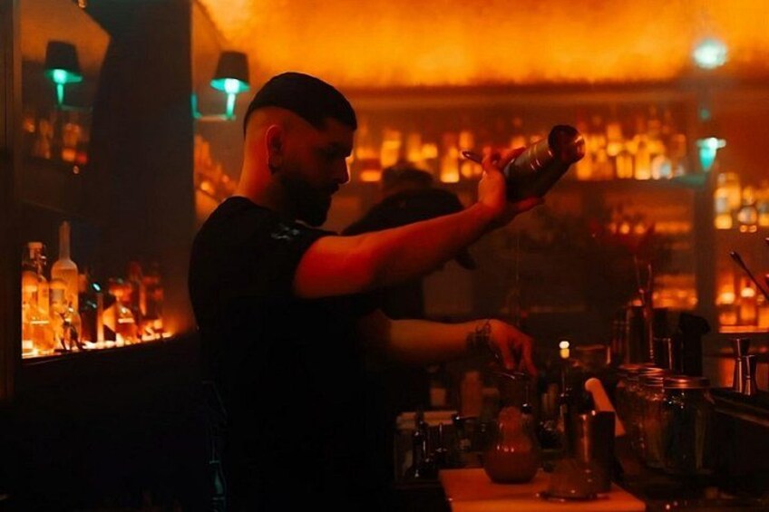 Un cantinero sirviendo una bebida en la barra, con botellas al fondo. 4