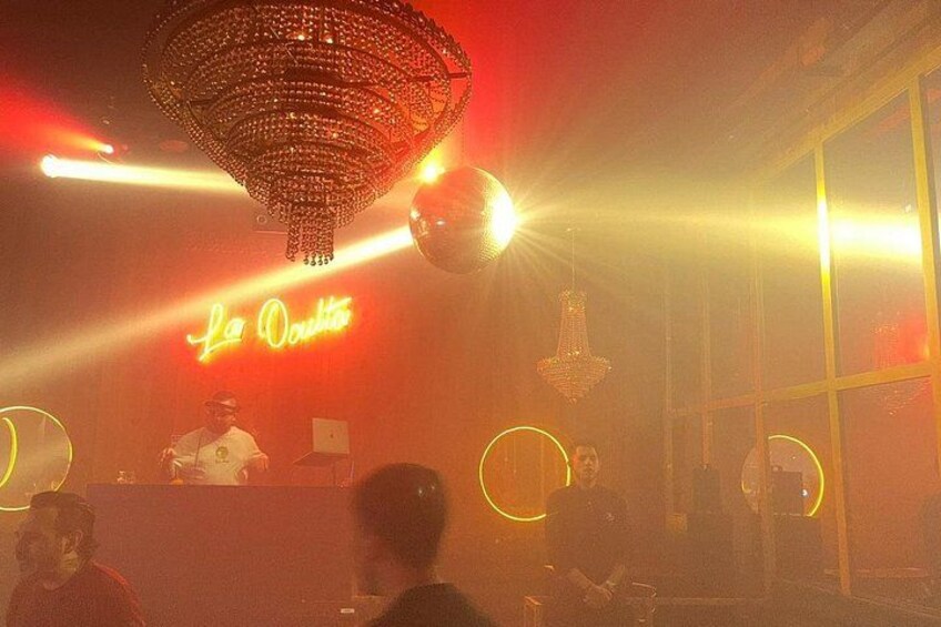Interior de una discoteca con letrero de neón, bola de discoteca y luminarias circulares. 3