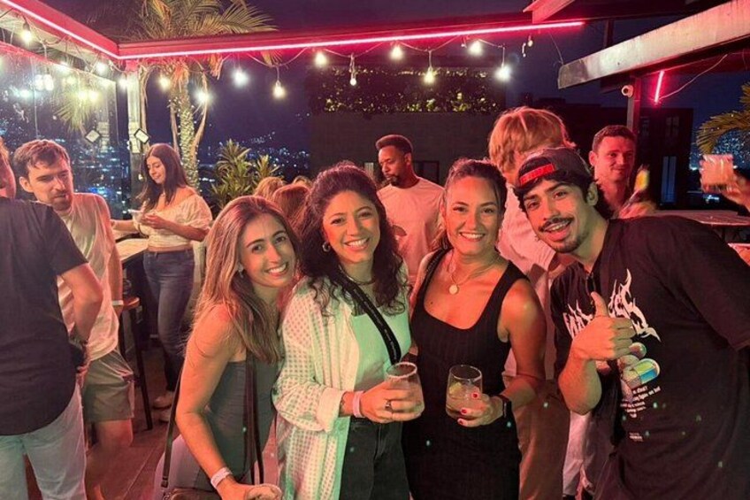 A group of people at an outdoor event with string lights and a cityscape in the background. 2