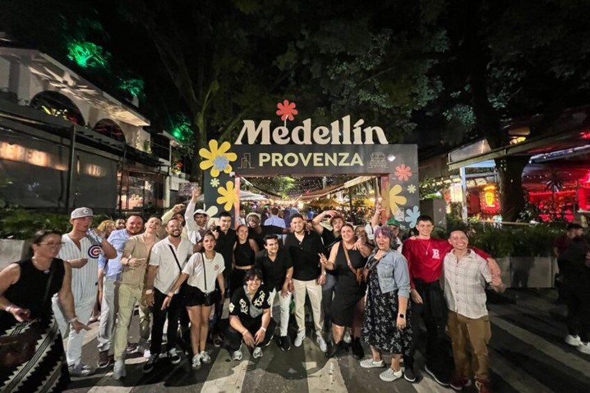 A group of people posing in front of a sign that reads 'Medellin Provence.' 1