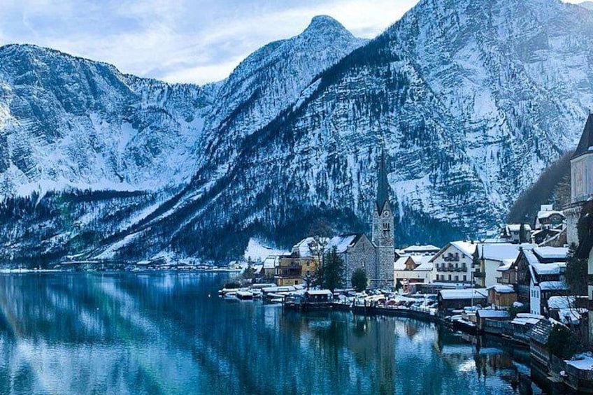 A snow-covered mountain landscape with a lake, a church, and a small village. 2